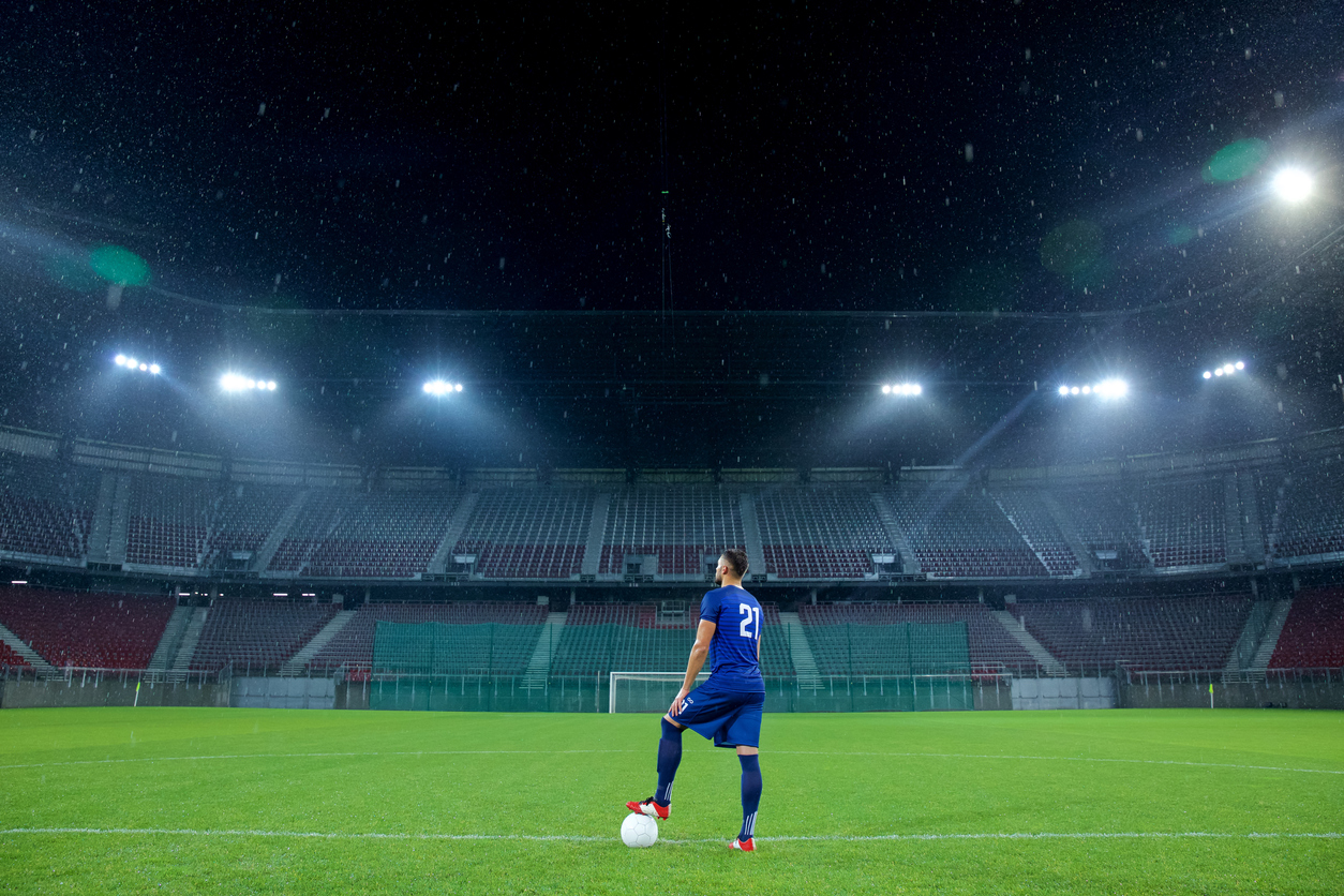 Soccer player stands in the field of an empty stadium